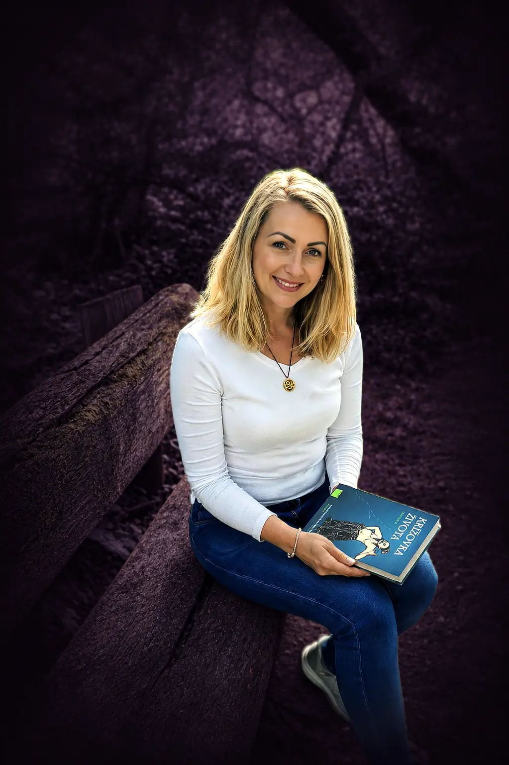 Monika sitting on a woodland bench, holding Dr Josef Jonáš's book